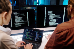 Close-up of two young developers working over data decoding software